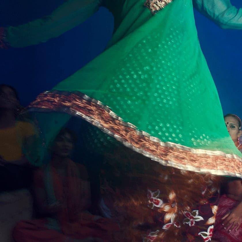 A green embroidered garment in motion above a gathering of people