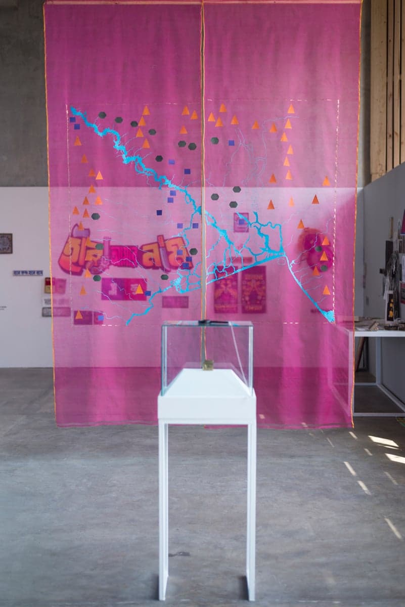A translucent pink woven textile suspended in a gallery